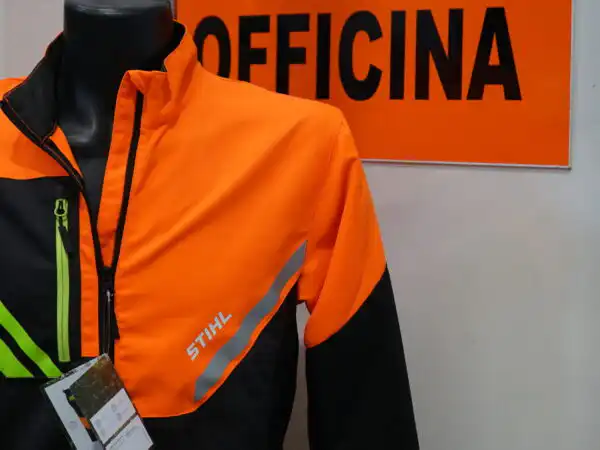 Giacca da lavoro protettiva STIHL arancione appesa accanto all'insegna Officina