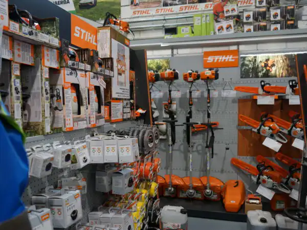 Parete espositiva STIHL con decespugliatori, tagliasiepi e accessori su pannello forato