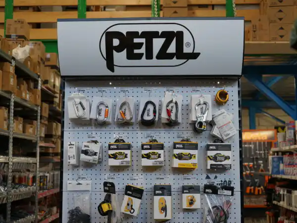 Espositore a parete Petzl con lampade frontali, moschettoni e accessori sicurezza