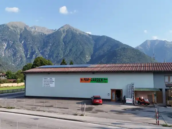 Vista aerea frontale ravvicinata della facciata e insegna Fer-Garden con montagne alle spalle