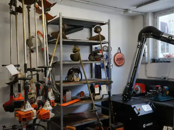 Officina di assistenza con decespugliatori appesi alla parete, scaffalatura e postazione di lavoro STIHL