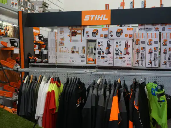 Reparto abbigliamento da lavoro STIHL con stender di capi sotto la parete espositiva brandizzata STIHL